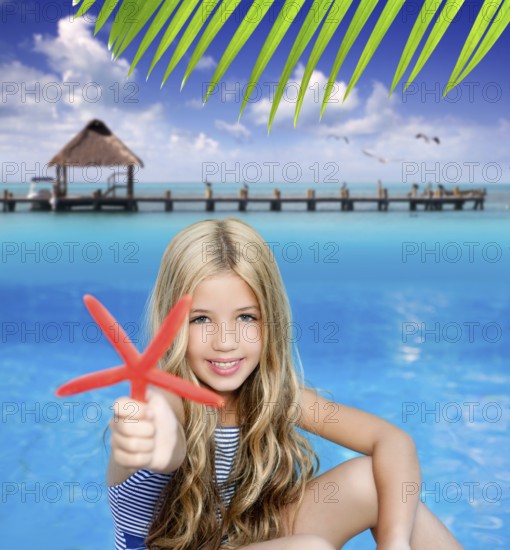 Children blond girl in summer vacation tropical beach with starfish