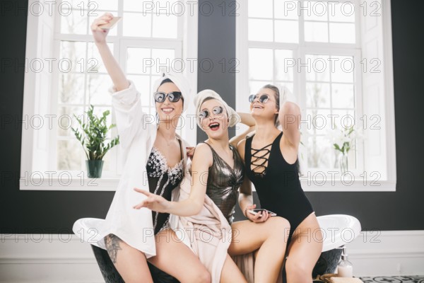 Picture showing group of happy friends in spa. girls with towels on heads having fun and taking selfie at home. Friendship, cosmetic, slumber party concept. Hen party with a bride in hotel