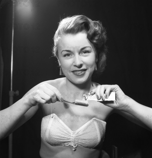 Brushing her teeth in the 1950s. A woman is pressing toothpaste onto her toothbrush. Sweden 1952. Photo Kristoffersson ref BH97-5