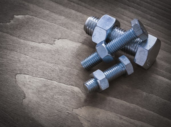 Construction nuts and screwbolts on brown wood board construction concept