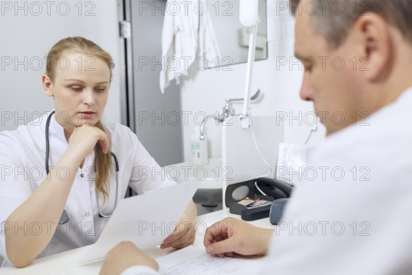 Doctor and nurse discussing analyses sitting at the table