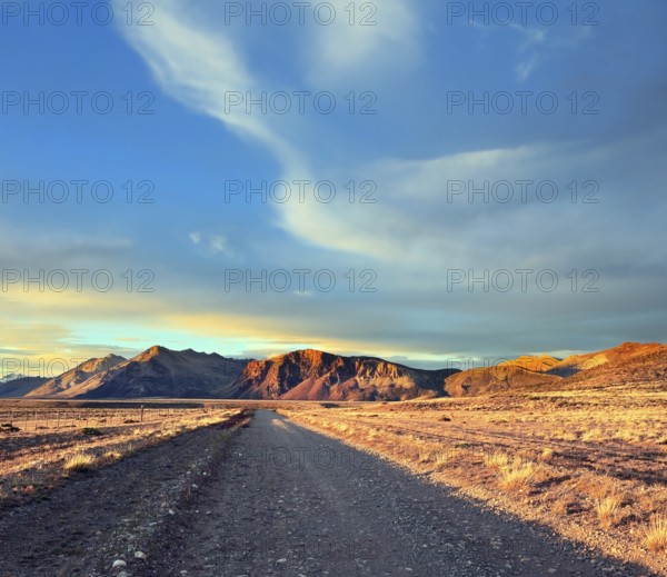 Argentine Patagonia. The gravel road between the endless pampas. The setting sun illuminates the mountains and steppe red