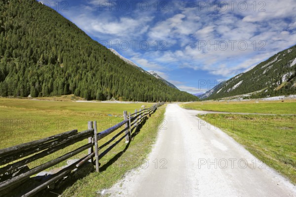 Headwaters National Park Krimml waterfalls. Rural idyll. Farm fields separated from the dirt road a low fence made ??of logs
