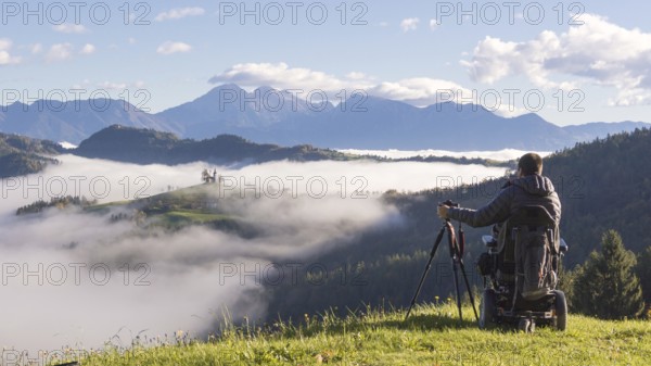 Man on wheelchair taking photos of beautiful landscape
