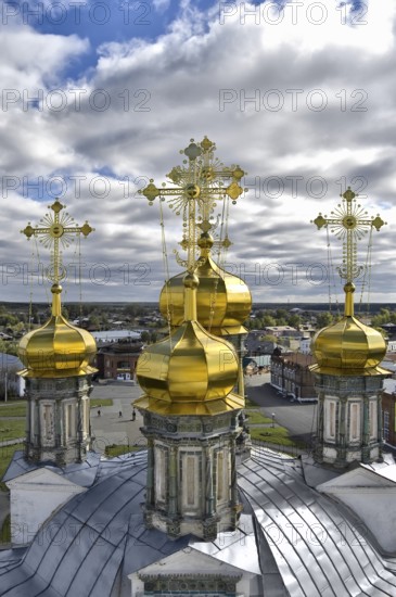 Golden domes of the Holy Trinity Cathedral in the background of the city, blue sky and white clouds (Verhoturie city of Sverdlovsk Region), Russia, Europe