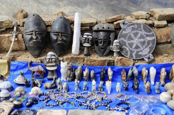 Various masks and sculptures displayed on a market stall with a blue ceiling, at the Tichka Pass, Col du Tichka, 2260m, Morocco, Africa