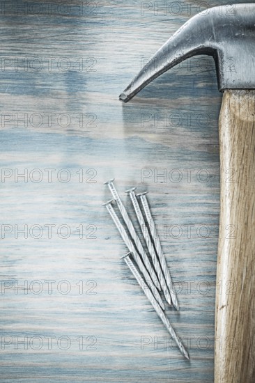 Vertical image of claw hammer nails on wooden board construction concept