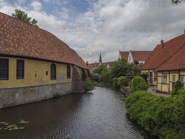 Historic half-timbered houses along a quiet river in dense vegetation, steinfurt, münsterland, germany