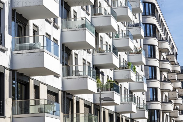 The façade of a white modern apartment block with many small balconies, seen in Berlin, Germany, Europe