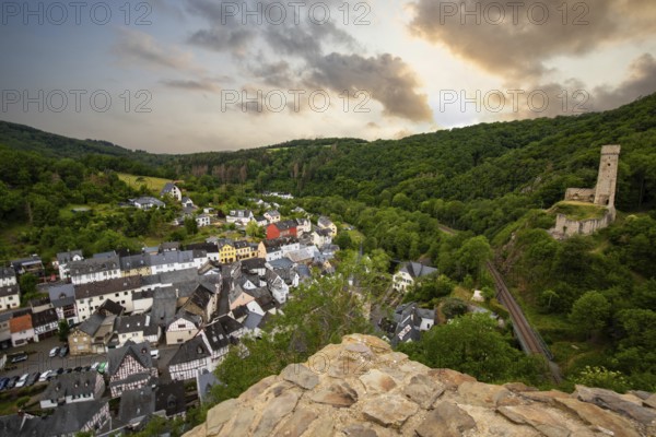 Landscape of a half-timbered village on a river, surrounded by hills and a castle. Beautiful nature in the town of Monreal am Elzbach, Germany, Europe