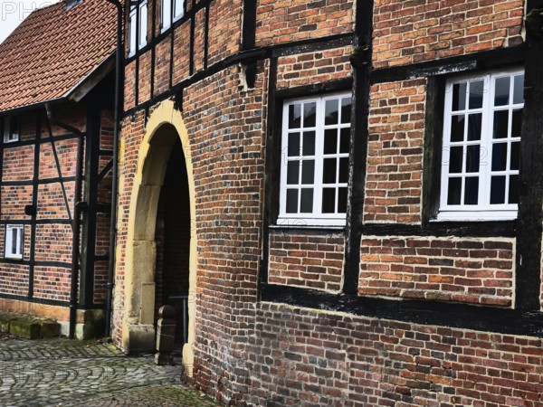 A close-up of a half-timbered house with brick walls and white windows, next to an archway, asbeck, legden, Münsterland, North Rhine-Westphalia, Germany, Europe