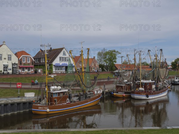 Fishing boats are anchored in the harbour, in the background houses and a maritime atmosphere, Greetsiel, East Frisia, Lower Saxony, Germany, Europe