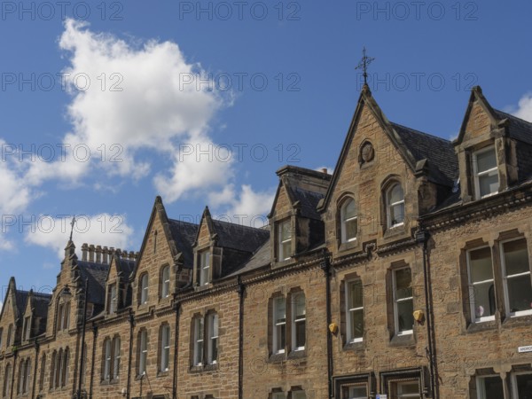 Row of historic buildings with pointed gables and stone facades under a blue sky in a cityscape, inverness, scotland, Great Britain