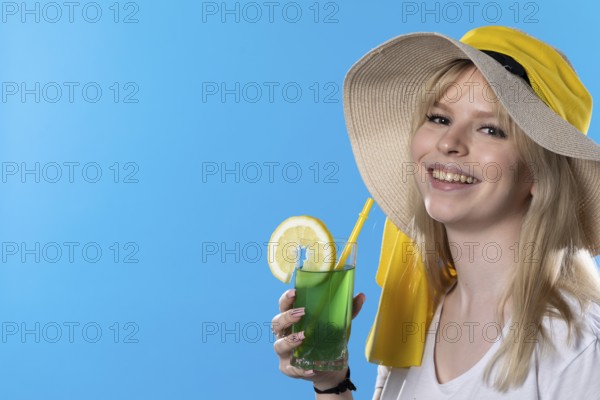 A teenager with an alcoholic drink in her hand and a large hat basks in the summer sun