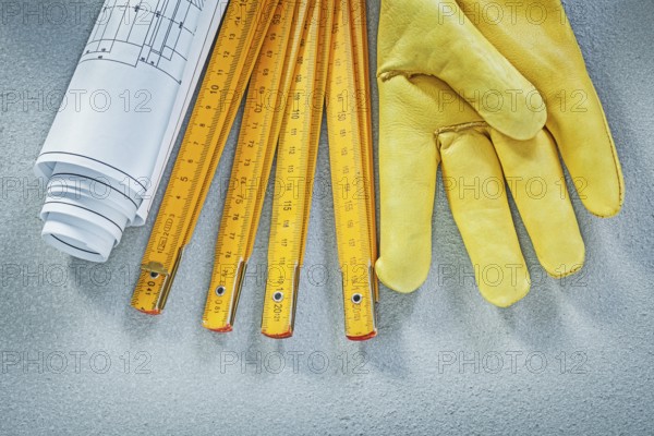 Set of safety gloves construction drawings wooden meter on concrete background building concept