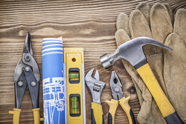 Construction level plan safety gloves claw hammer gripping tongs steel cutter adjustable wrench on wooden board