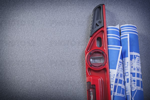 Construction level blue rolled blueprints on grey background copy space maintenance concept