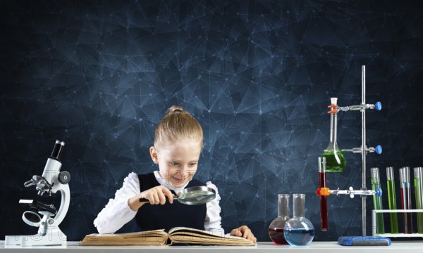 Little girl sitting at desk with magnifier and open book. Research and education in school. Happy schoolgirl in school wear carefully studying book. Clever girl reading book with magnifying glass
