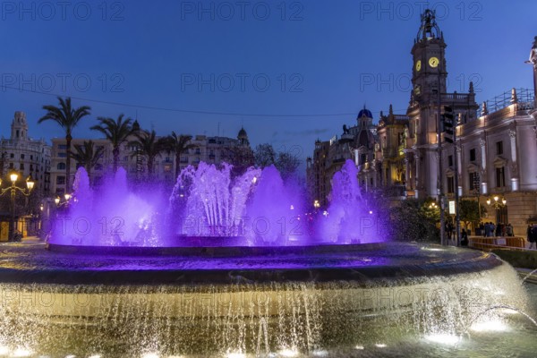 Night photo with purple illuminated water round fountain and blue sky in the centre of the old town in La Plaza del Ayuntamiento (Plaza Ayuntamiento), Valencia, Valencian Community, Province of Valencia, Spain, Valencia, Valencian Community, Province of Valencia, Spain, Europe