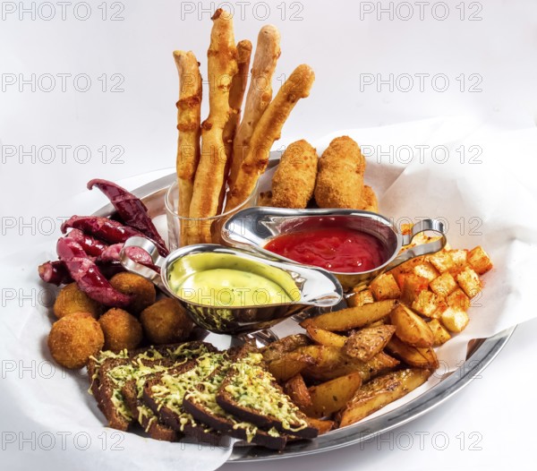 Large plate with a wide selection of snacks for beer served with two kinds of sauce on a white background