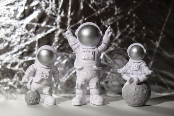 Three Plastic toys figure astronaut on silver background Copy space. Concept of out of earth travel, private spaceman commercial flights. Space missions and Sustainability