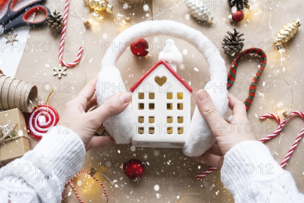 Cozy house in Christmas decor layout, warm knitted scarf, hat, winterization. Winter, snow, home insulation, protection from cold weather, room heating system. Festive mood, Christmas, New Year