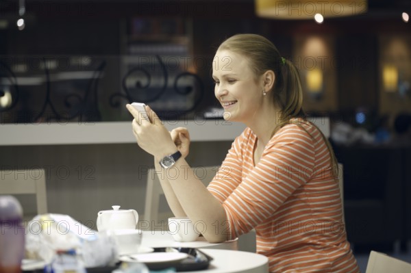 Young beautiful woman chatting on smartphone sitting in cafe