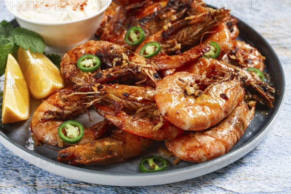 Grilled shrimps served with hot sauce and slices of fresh lemon, homemade, no people