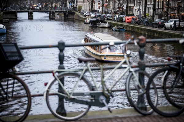 A canal tour boat navigates the web of canals in the central region of the city of Amsterdam, The Netherlands, Europe