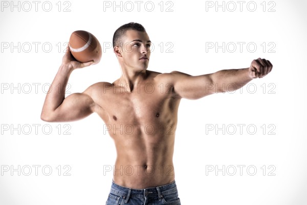 Handsome, athletic young man shirtless, throwing american football ball, isolated on white