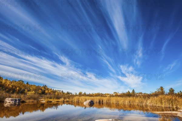 Cirrus clouds are reflected in the Winnipeg River. Wonderful autumn day. Old Pinawa Dam Park. The concept of ecological and recreational tourism