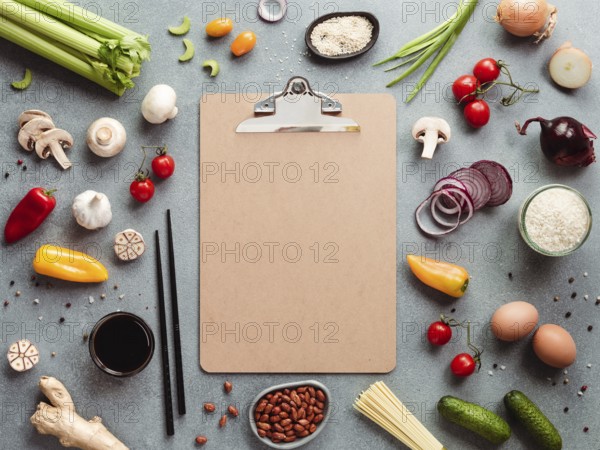 Asian ingredients and empty clipboard. Various of Chinese cooking ingredients and chopsticks on gray stone background. Asian food recipes concept. Copy space for text. Top view or flat lay