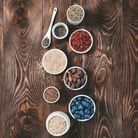 Various superfoods in small bowl on wooden table.Selection super food.Superfood as blueberry, chia, raw cocoa bean, goji, hemp seeds, quinoa, brown rice.Copy space for text.Top view or flat lay.Square