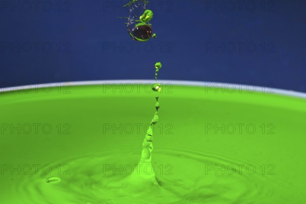 Green liquid splashes in a dynamic moment against a blue background, water droplets, collision, high-speed photography, concept, figures