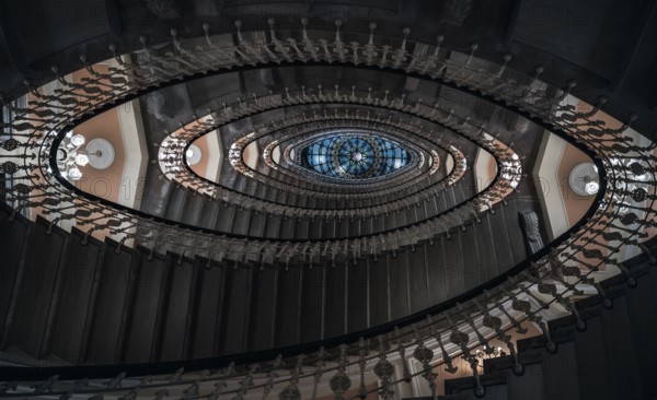 Eye-catching image with staircase design in a spiral form, a pattern of oval figures, illuminated by chandeliers, viewed from under, in Genoa, Italy, Europe