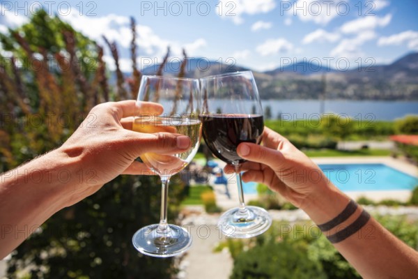 Okanagan Valley wine tasting tour, wineries visit during summer and spring vacations concept, man and woman hands toasting red and white wine glasses