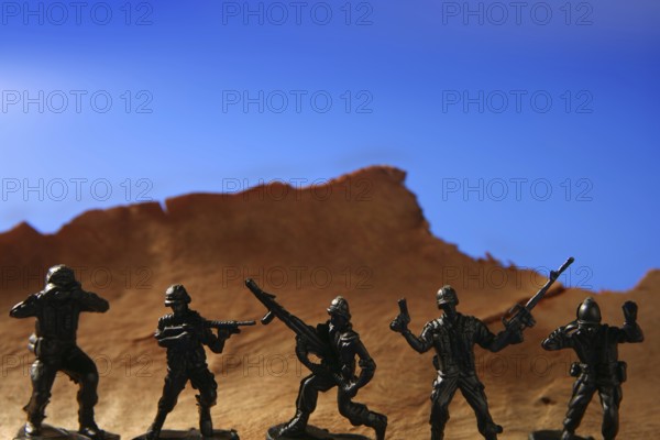 War metaphor, toy little soldiers fighting on wooden mountain