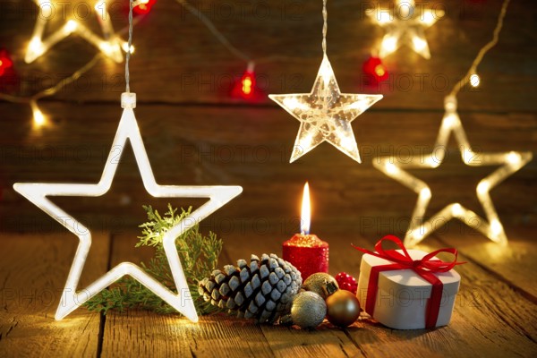 A candlelit wooden table with gifts, pine cones, and star lights