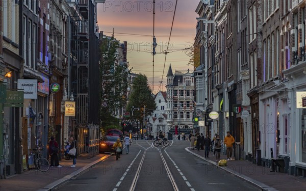 A picture of a street in Amsterdam at sunset