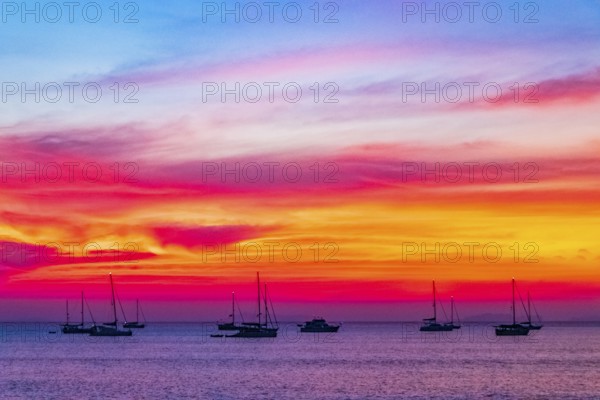Yachts boats in front of the most beautiful colorful sunset at Tropical Paradise island Koh Phayam Ao Khao Kwai Beach in Ranong Thailand
