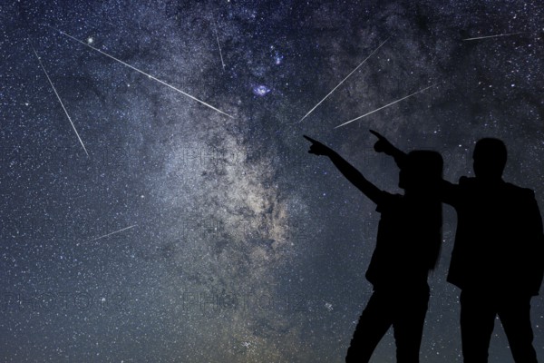Silhouette of young couple watching Meteor Shower. Nigh Sky