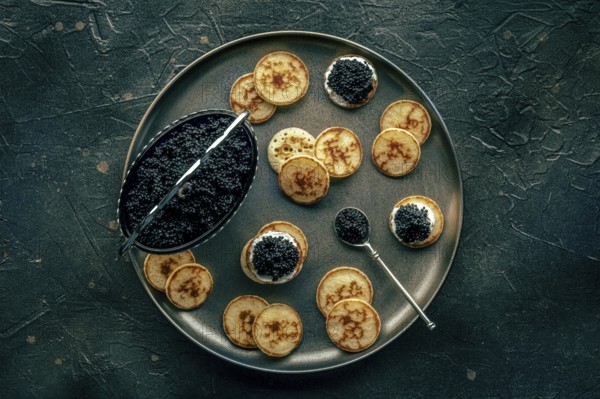 Blinis with black caviar and cream cheese, overhead flat lay shot on a black background, mini pancakes, an elegant appetizer, Food photography, Food photography