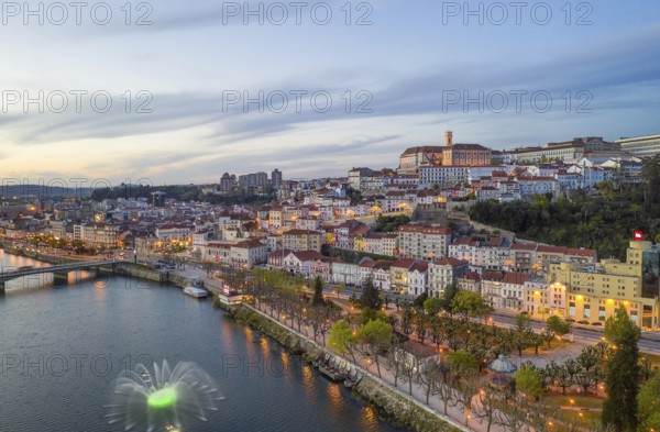 Coimbra drone aerial city view at sunset with colorful fountain in Mondego river and beautiful historic buildings, in Portugal