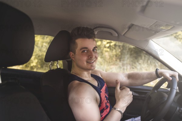 Portrait of smiling young man sitting in a car and looking at the camera on a sunny day