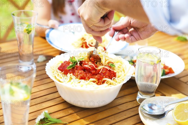 Family dinner variety of Italian dishes on wooden table in the garden