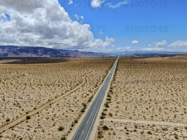 Aerial view of endless desert straight dusty asphalt road in Joshua Tree Park. USA. Long straight tarmac road heading into the desert to the direction of Arizona