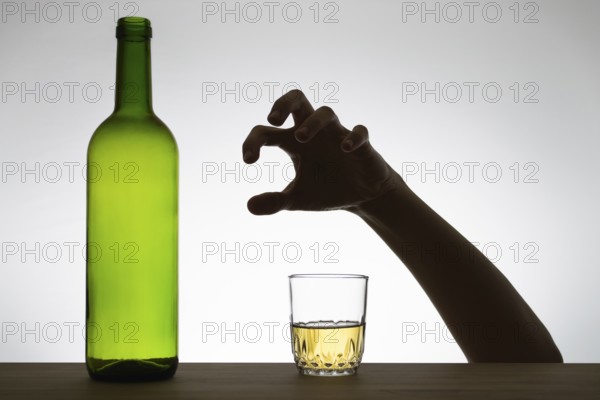 Silhouette of a hand reaching for a glass of wine