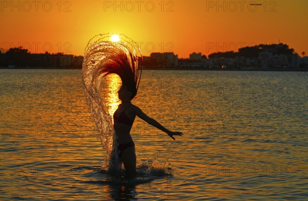 Girl flipping hair flip at sunset beach in orange sky