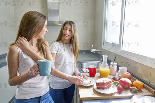Best friends girls teens breakfast in kitchen having fun
