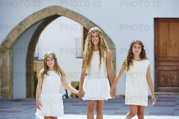 Kid girls walking hand in hand at white Mediterranean village of Spain